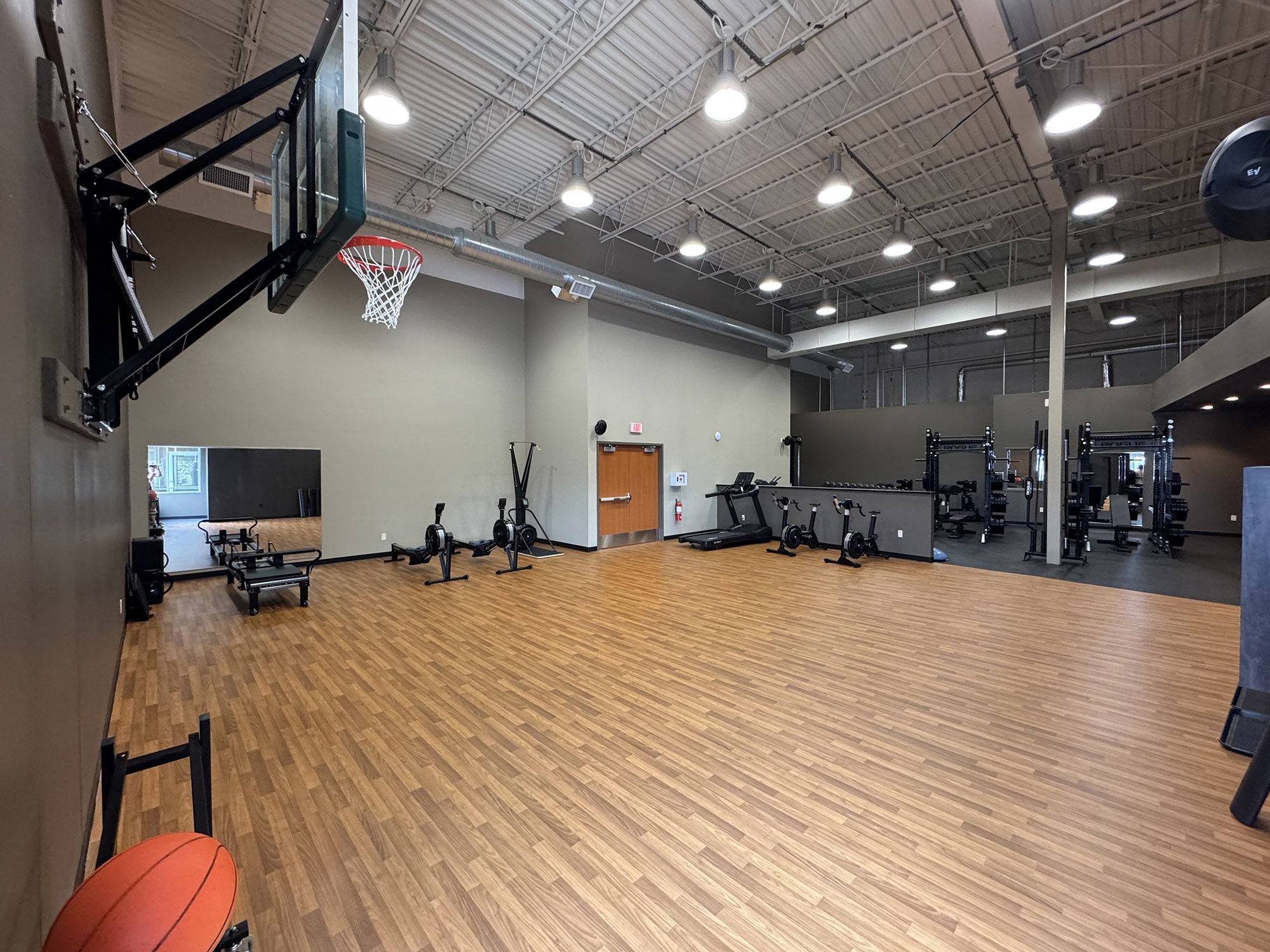 Spacious training gym with a basketball hoop, cardio machines, and weightlifting equipment.