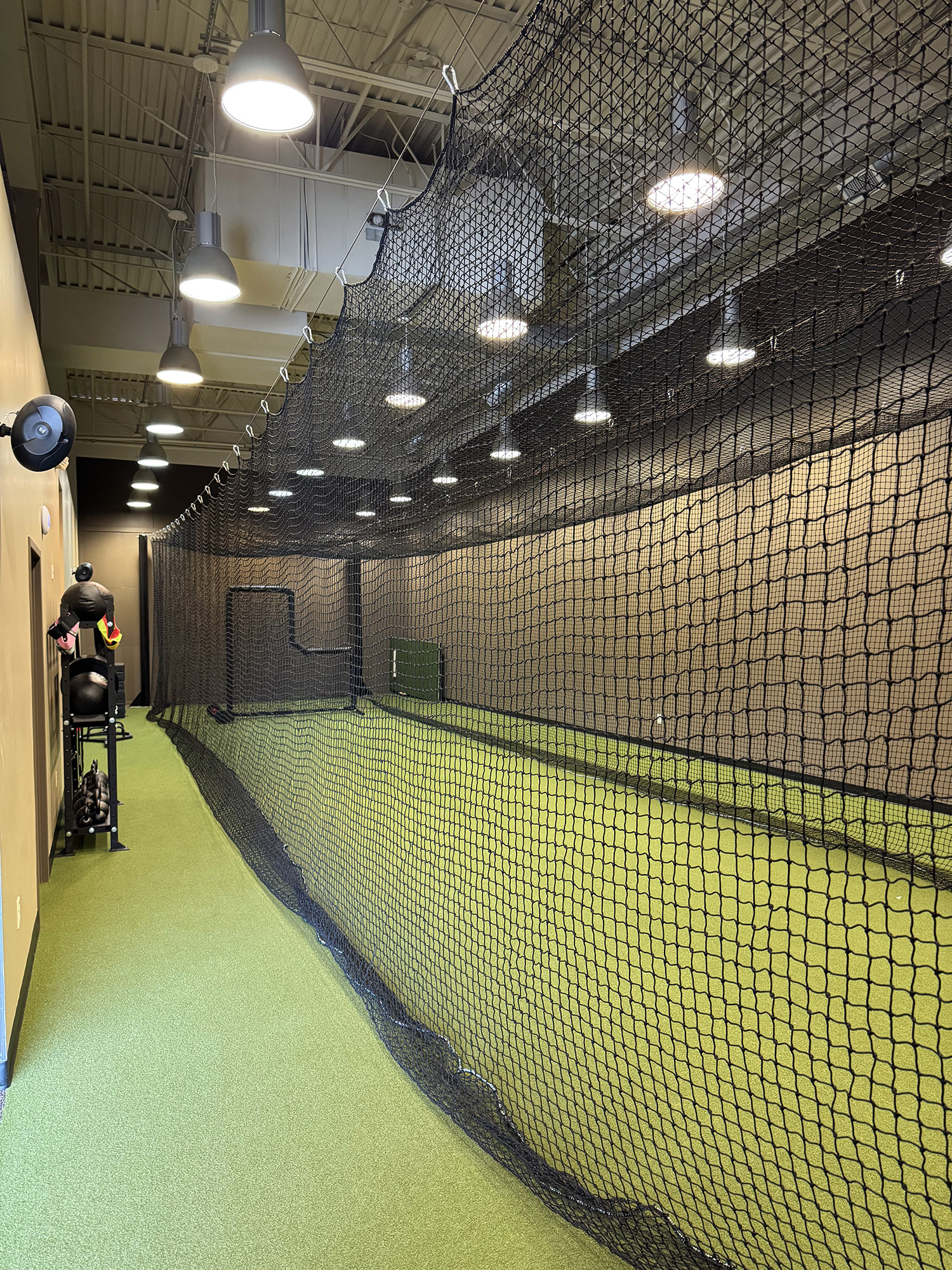 Indoor sports training lane enclosed by protective netting.