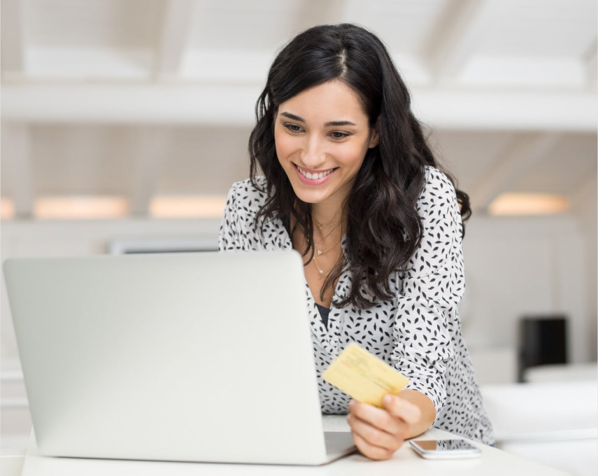 Woman on a computer paying her bill with a cred card while using a laptop.